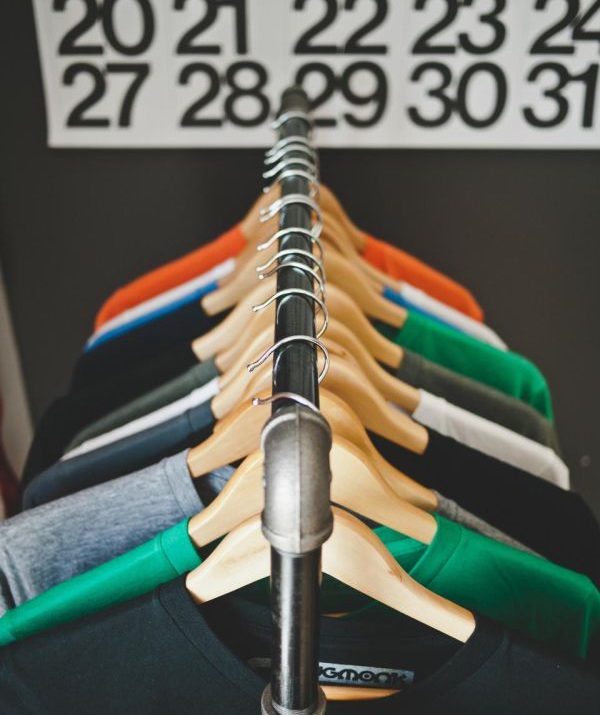 Shirts in several colours on wooden hangers on a metal rail