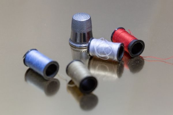 Thimble and spools of thread on a grey metal surface